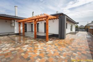a patio with a wooden pergola on a house at Szentmiklósi Vendégház Gyulaháza in Gyulaháza