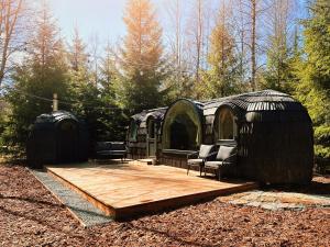 a wooden deck with two domes and chairs in a yard at Pedaspä Igloo House and Sauna in Pedaspea