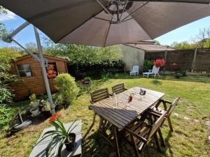 einen Holztisch und Stühle mit Sonnenschirm im Hof in der Unterkunft Tiny house avec jardin spacieux in Saint-Nazaire