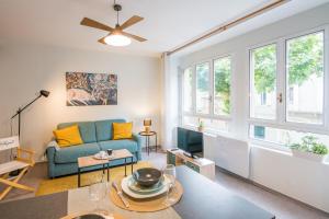 ein Wohnzimmer mit einem blauen Sofa und Fenstern in der Unterkunft Cardabelle - Joli appt pour 2 avec parking privé in Millau