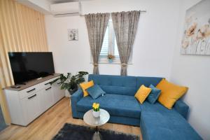 Palomino apartment في سيني: غرفة معيشة مع أريكة زرقاء وتلفزيون