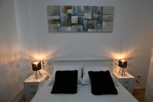 Palomino apartment في سيني: غرفة نوم مع سرير أبيض مع مصباحين على الطاولات