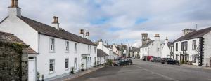 una strada con case bianche e auto parcheggiate sulla strada di Woodlyn Guest House a Gatehouse of Fleet