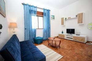 ein Wohnzimmer mit einem blauen Sofa und einem TV in der Unterkunft B91 - Bairro Apartment in Lagos in Lagos