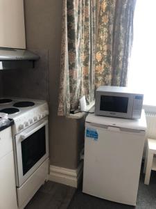 a kitchen with a stove and a microwave on top of a refrigerator at Cosy studio in Mill Hill