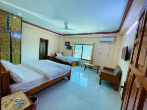1 dormitorio con 2 camas y TV. en Kashmir Heaven Guest House en Muzaffarabad