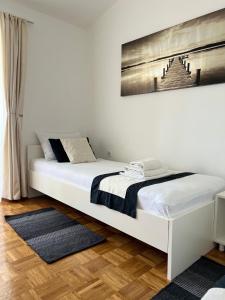 a white bed in a bedroom with a picture on the wall at Apartments Loncar-near Zrće beach in Novalja