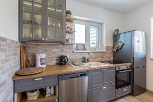 a kitchen with gray cabinets and a stainless steel refrigerator at Apartman Sandra in Malinska