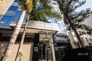 un hotel con una palmera frente a un edificio en Le M Hôtel, en Rabat