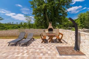 a patio with a table and chairs and a fireplace at Apartman Sandra in Malinska