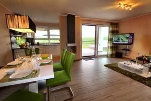 a kitchen and living room with a table and green chairs at Ferien_HAUS LIMERICK in Göhren-Lebbin