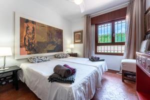 a bedroom with a white bed with a painting on the wall at Art Gallery House in La Cala de Mijas