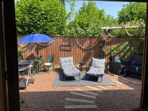 een patio met stoelen, een tafel en een parasol bij Charming Gnome Cottage in Devon near Sidmouth in Ottery Saint Mary