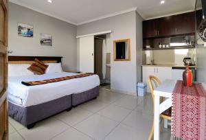 a hotel room with a bed and a table and a kitchen at Ballito Backpackers in Ballito