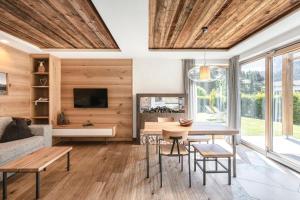 sala de estar con techos de madera, mesa y sillas en Apartments Chalet Anna, en Ortisei
