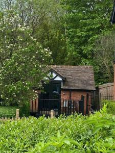 un pequeño edificio con una puerta negra en un jardín en Robin's Nest - a self contained detached annex with sky sports & movies en Newborough