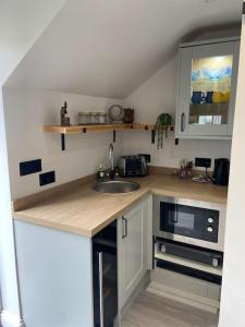 a small kitchen with a sink and a microwave at Robin's Nest - a self contained detached annex with sky sports & movies in Newborough