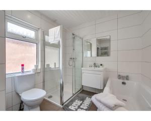 a white bathroom with a toilet and a tub and a sink at Central Belfast Apartments Ballyhackamore in Belfast