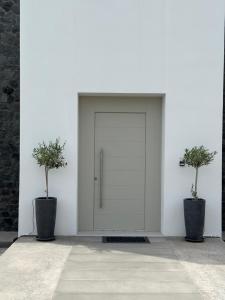 a white garage door with two potted trees in it at Kaminos Private Villa in Vóthon