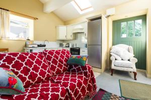 a living room with a red couch and a kitchen at The Manor Stables at Moyglare Manor in Maynooth