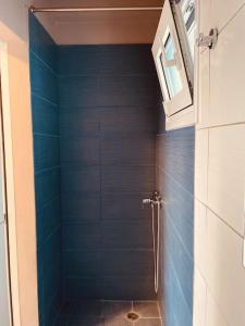ein Bad mit einer Dusche und blauen Fliesen in der Unterkunft Tiny rooftop apartment in Athen