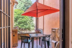 uma mesa e cadeiras com um guarda-sol vermelho num pátio em La casa di Ida em Pescia