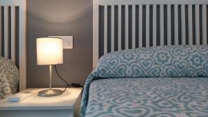 a bedroom with a bed and a lamp on a night stand at Sherryflat Arroyo in Jerez de la Frontera