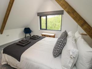 um quarto com uma cama branca com almofadas e uma janela em The Larches em Bishops Castle