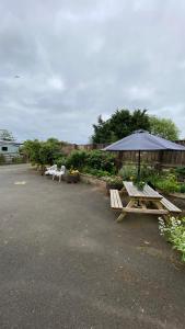 two picnic tables and an umbrella in a parking lot at Wheelhouse - Grinkle Bell Cottage in Saltburn-by-the-Sea