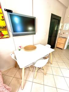 einen weißen Tisch mit Stühlen und einen TV an der Wand in der Unterkunft Sunny & Bright in Komotiní