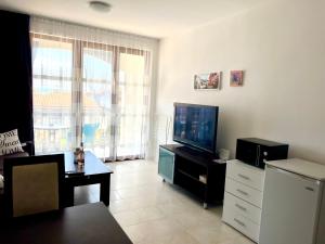 uma sala de estar com uma televisão de ecrã plano e uma mesa em Apartment Marina beach k-s Triumph em Sveti Vlas