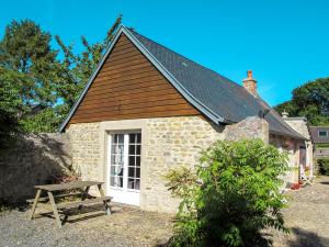 ein kleines Cottage aus Stein mit einer Picknickbank davor in der Unterkunft Holiday Home Les Lutins - COM400 by Interhome in Commes