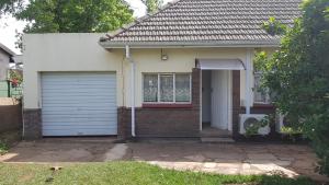 a small house with a garage and a window at Crafty Coal Stove in Pietermaritzburg