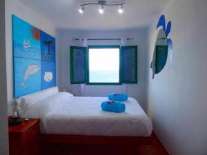 1 dormitorio con 1 cama con tabla de surf en la pared en Apartamento Vacacional Barquito en Playa Quemada, en Playa Quemada