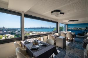 um restaurante com mesas e cadeiras e janelas grandes em Askadar May Otel em Istambul