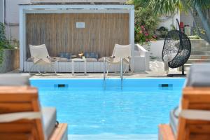 a pool with chairs and a table and a couch at Aktaion Beach Boutique Hotel & Spa in Skala