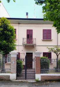 a white house with red shutters and a gate at Attic in Rimini