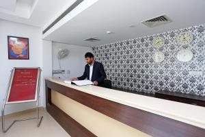 a man is standing at a reception desk at Flagship Telone stay in Garhi Harsāru