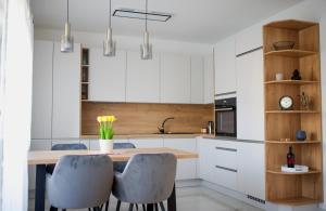 a kitchen with white cabinets and a wooden table and chairs at Apartman Plum - SELF CHECK IN, FREE PARKING in Osijek