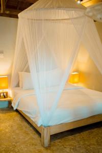 a bedroom with a white bed with a canopy at BUNGALOW CAFE GILI BEACH FRONT in Gili Meno