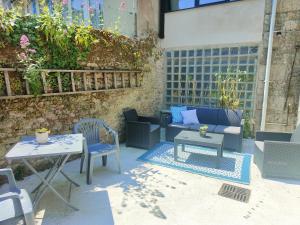 patio ze stołem, krzesłami i kanapą w obiekcie La petite maison w mieście Dinan