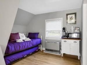 a bedroom with a purple bed and a microwave at The Thistle Inn in Boothbay Harbor