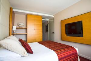 a hotel room with a bed and a flat screen tv at Le Churchill Hôtel & Spa in Carnac