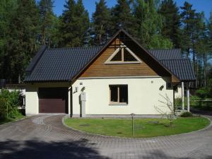 una casa bianca con tetto nero e vialetto di House in Pine forest Asari a Jūrmala