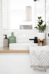 une salle de bain blanche avec un lavabo et une plante dans l'établissement Sanbis Cabin - hidden boutique retreat, sea views, à Aldinga Beach 22 autres photos