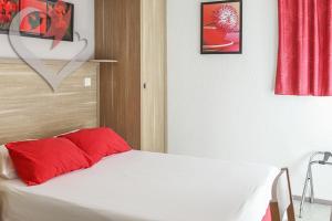 Un dormitorio con una cama blanca con almohadas rojas. en HOTEL RESTAURANT OLYMPE, en Aix-en-Provence