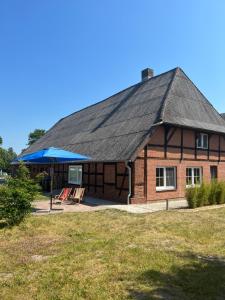 a building with a roof with chairs and a blue umbrella at Ferienwohnung Elbsegler in Bleckede