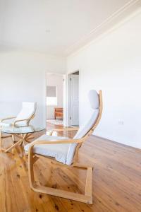 Duas cadeiras brancas num quarto com pisos em madeira em Kiama Beach House & Private Beach & Newly Renovated em Kiama