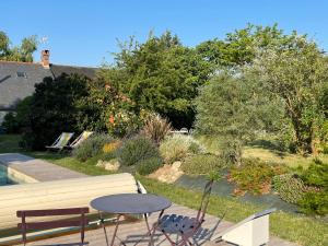 a patio with a table and a bench and trees at Chambres d hôtes avec Piscine et Spa La Folière Saumur in Villebernier