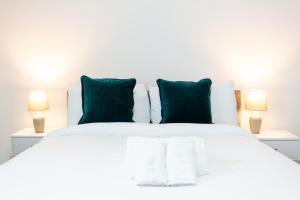 a white bed with green pillows and two lamps at Beach Walk by Sorted Stay in Southend-on-Sea